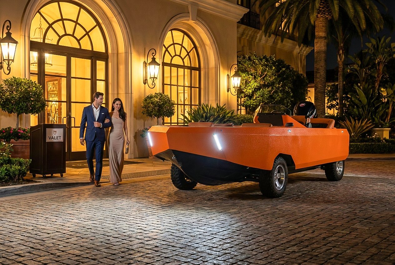A couple beside an orange WaterCar outside a waterfront restaurant at night
