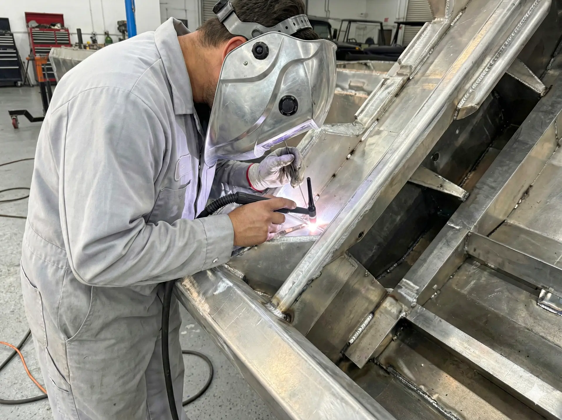 A technician hand-welding the internal structure of an aluminum WaterCar hull.