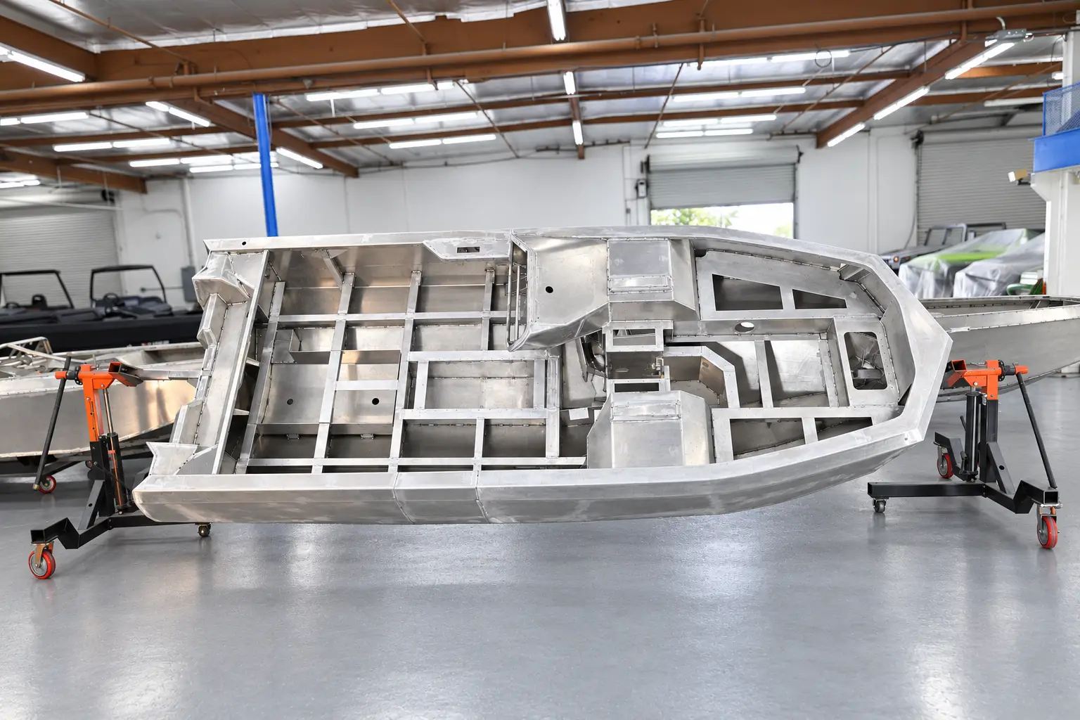 Side view of an unfinished aluminum WaterCar hull on a build fixture, showing its internal reinforcements.
