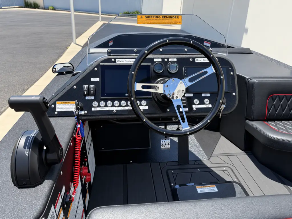 WaterCar cockpit with steering wheel, road and water displays, rocker switches and marine throttle.