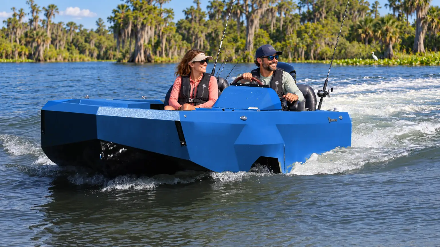 A couple wearing life jackets cruises in a blue WaterCar Adventure past a cypress-lined lake.